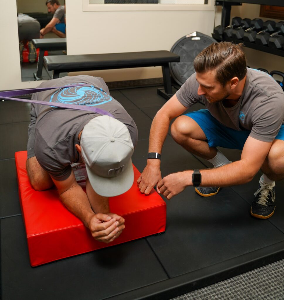 a man kneels down as another man kneels down on a bench.