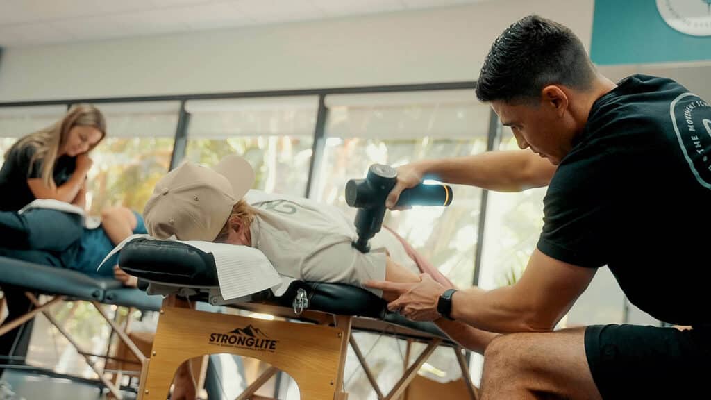 An employee at The Movement Schopp performing physical therapy treatments on a client with a tool to massage the muscles